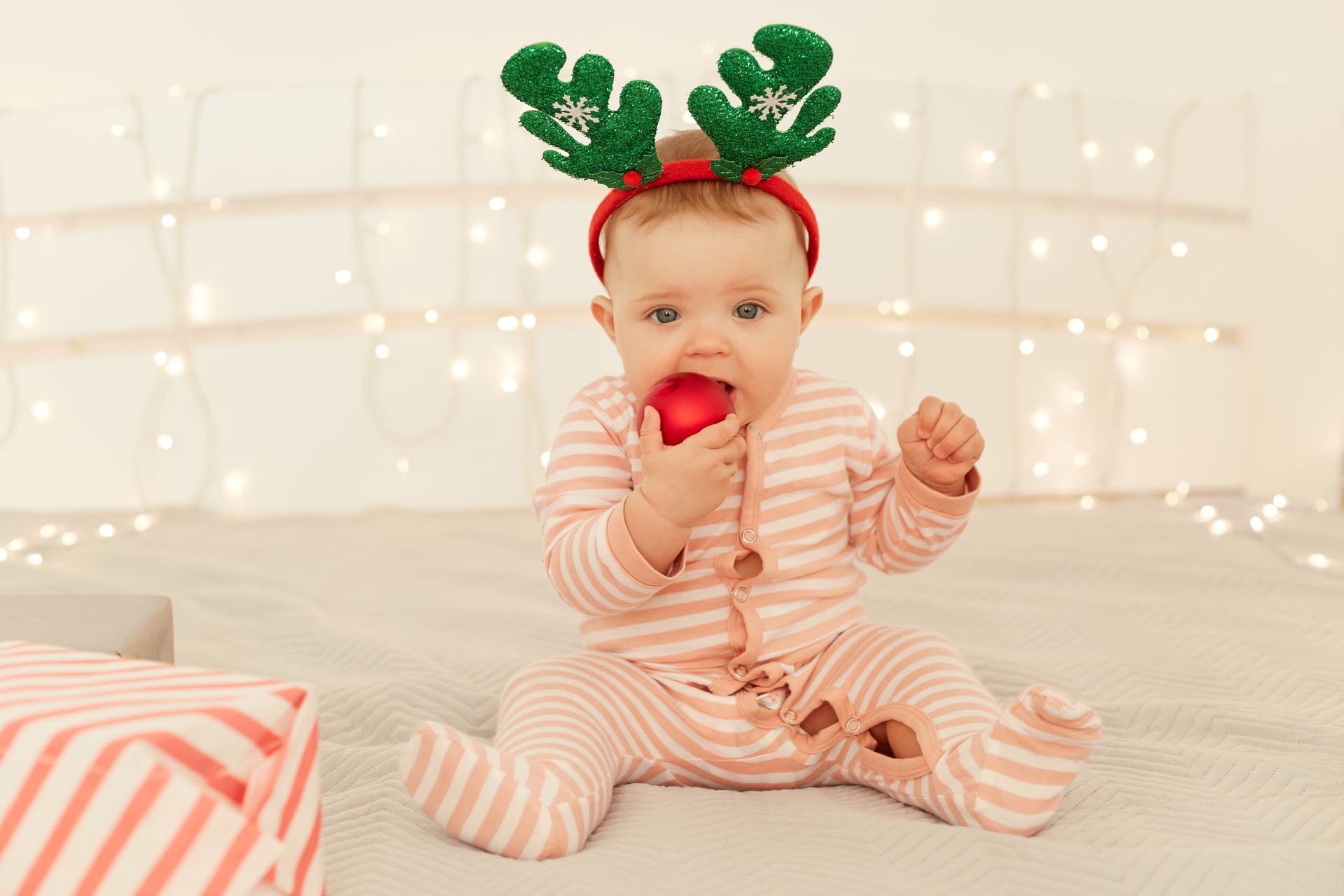 Baby Safe Christmas Decorations - Baby chewing bauble with lights in background